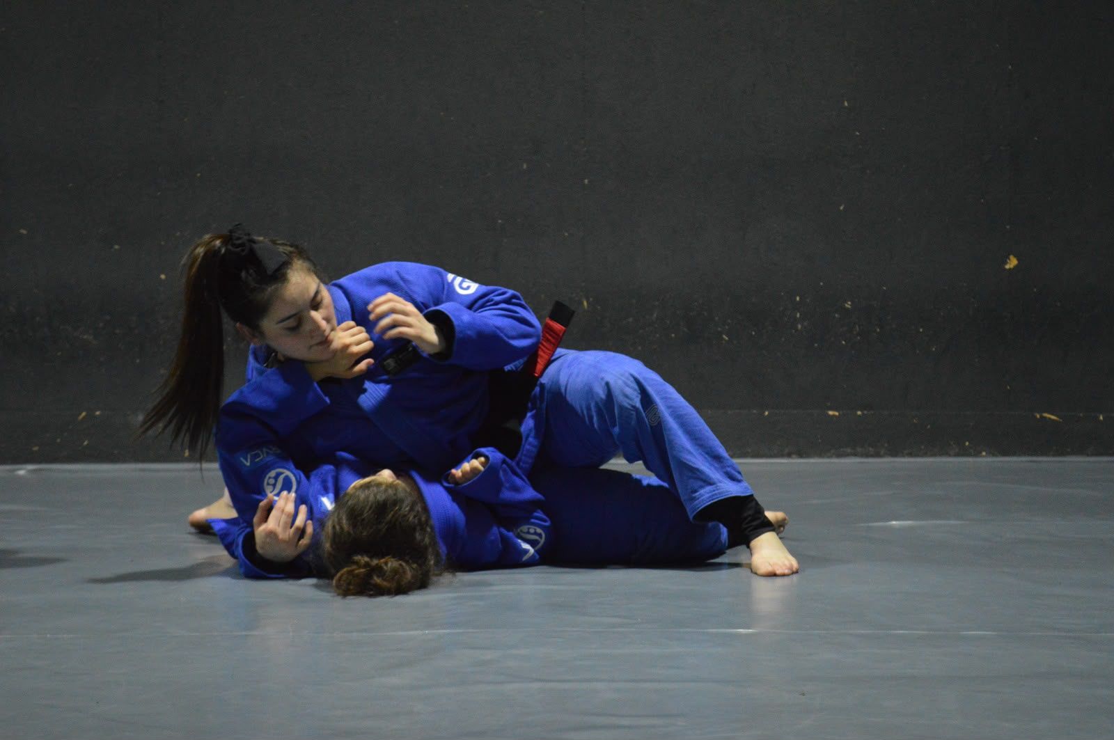 Dos personas con kimono azul practican control en el suelo sobre el tatami